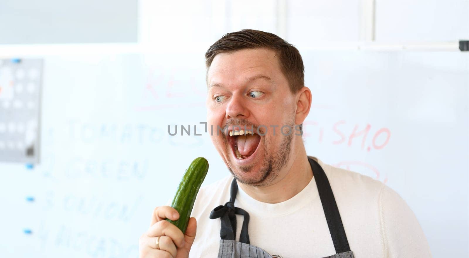 Professional Chef Eating Green Organic Cucumber. Man with Beard Hold Fresh Vegetable. Healthy Vegetarian Recipe Ingredient. Natural Vegan Nutrition. Cook Holding Food for Dieting Horizontal Photo.