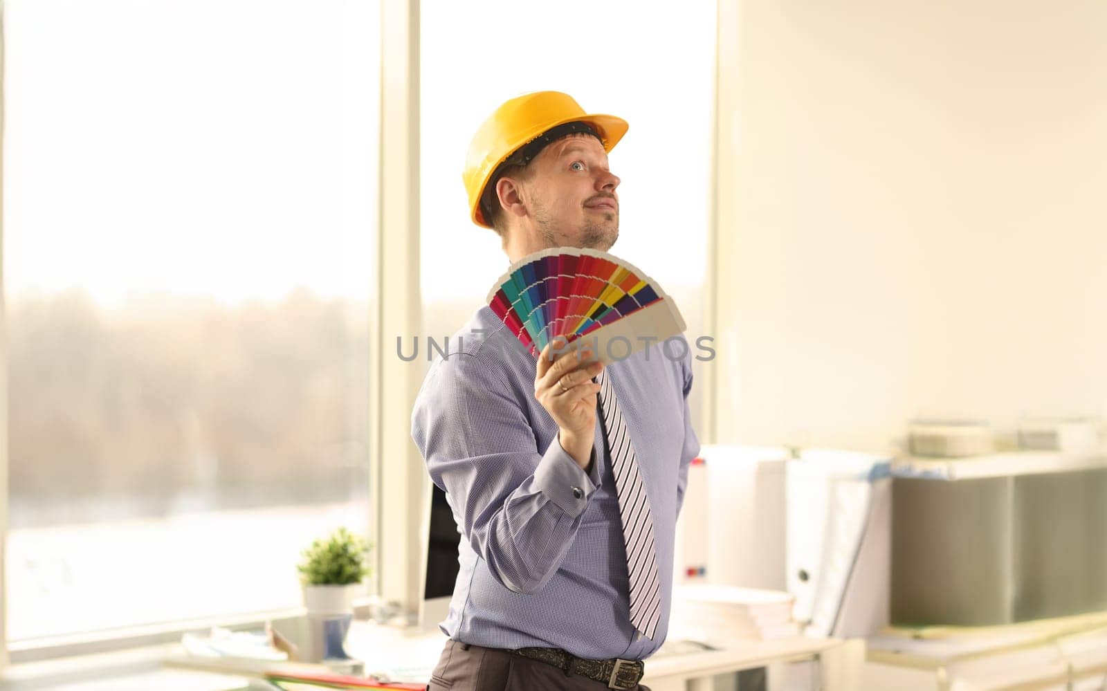 Male Caucasian Decorator Holding Colour Swatches. Happy Engineer Looking Up. Creative Architect Man Wearing Protective Casque, Formal Shirt and Tie Front Shot. Decoration Print Spectrum