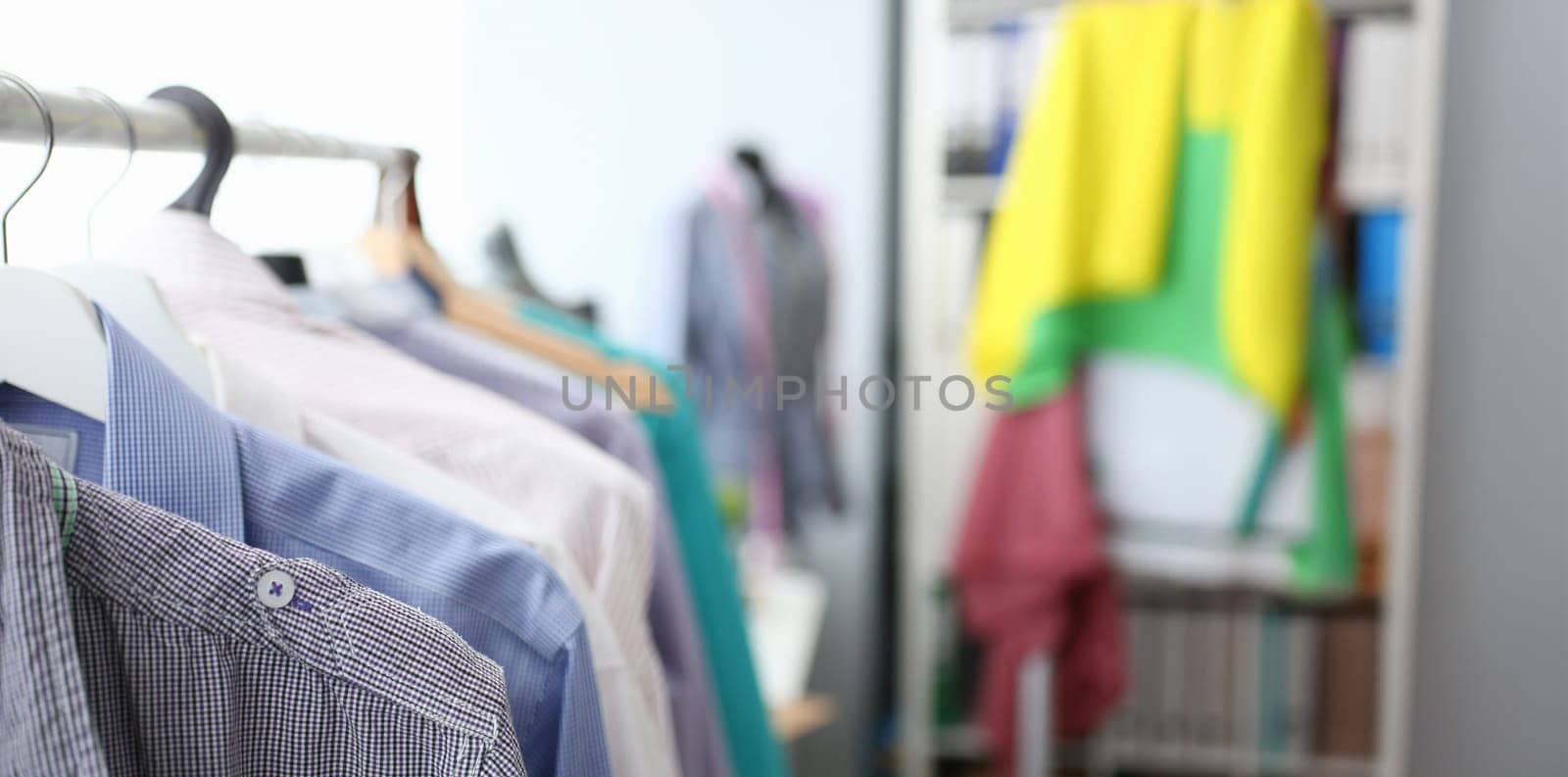 Fashion Creative Clothes Design Studio Concept. Fashionable Trendy Dress on Hangers. Various Colors Man Shirts Collection Hanging on Rack. Empty Dressmaking Workplace Cozy Interior