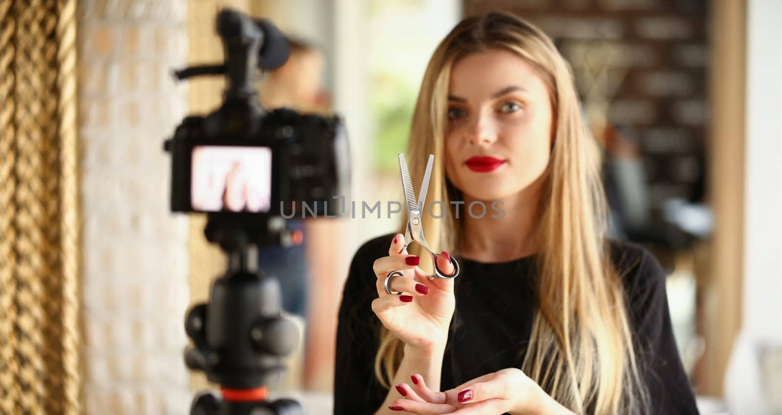 Blonde Woman Blogger Holding Metallic Scissors. Hairdresser Recording Modeling Instrument for Beauty Blog. Hairstylist Showing Cutting Tool on Camera. Girl with Styling Shear Looking at Camera Shot