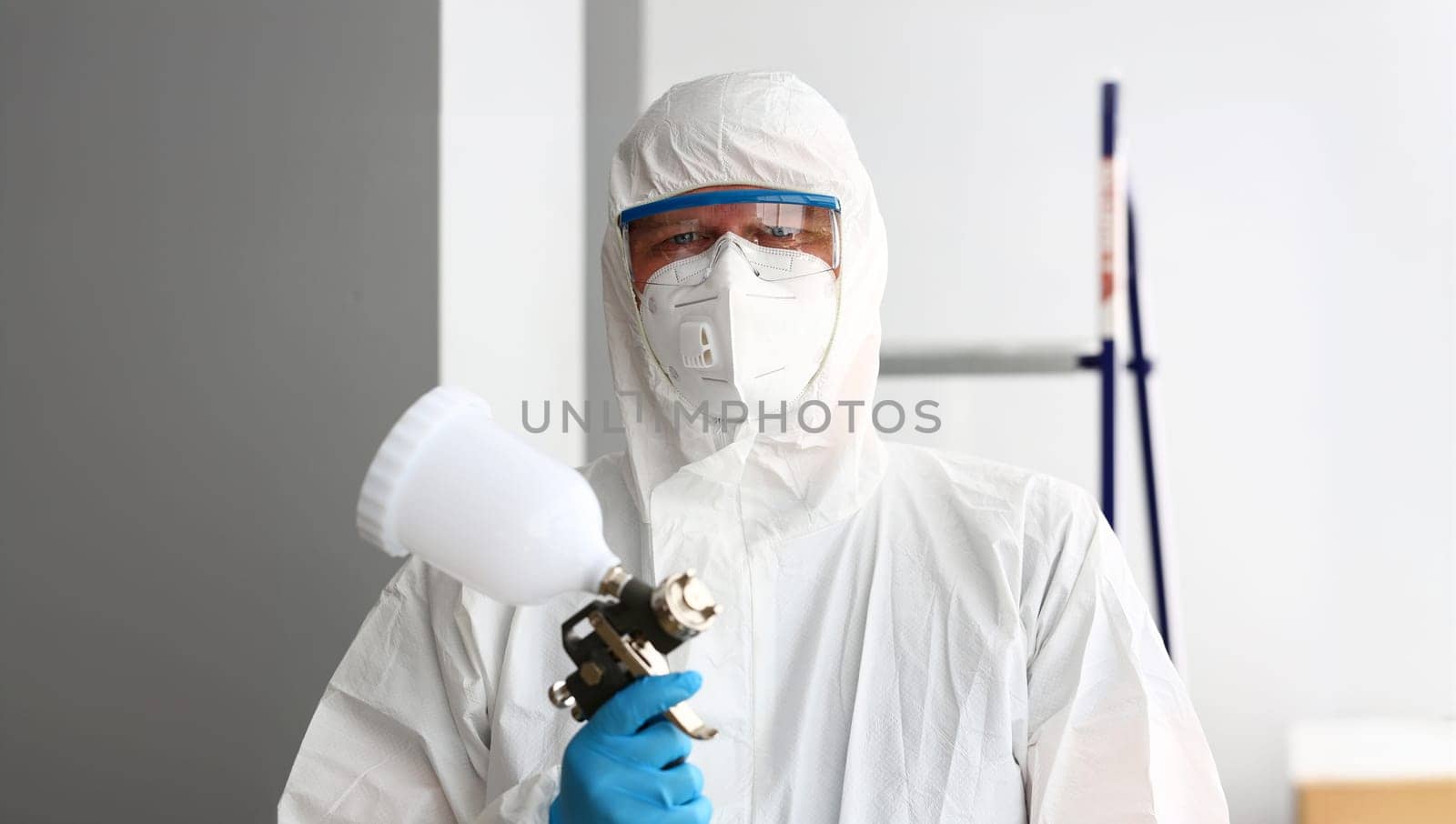 Workman hold in arm airbrush gun wearing protective suit portrait