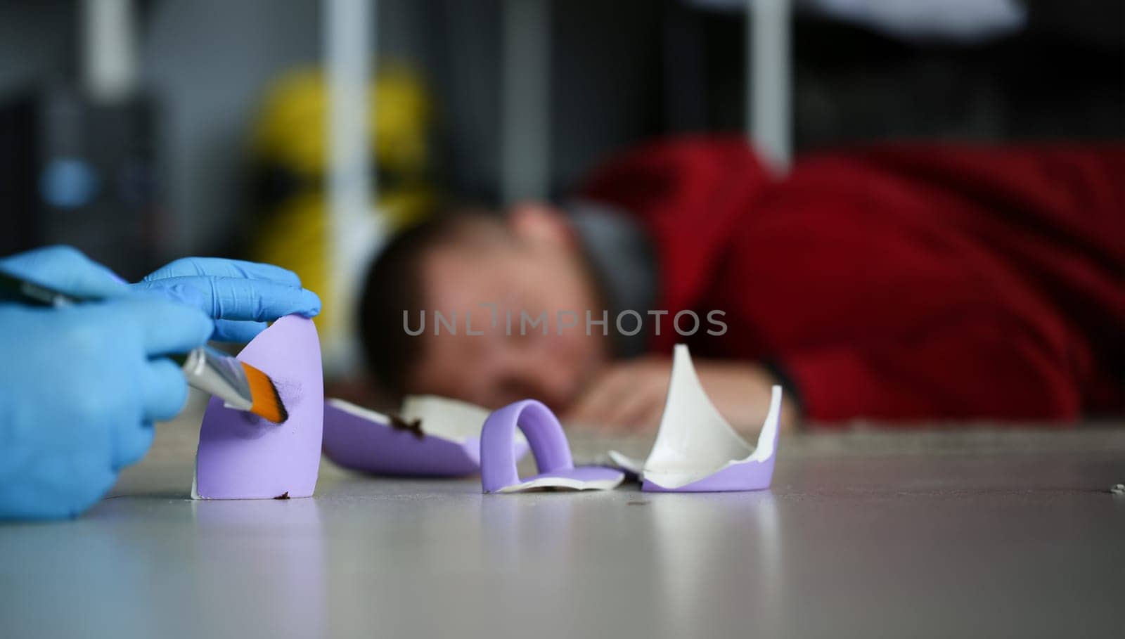 Male forensic expert in protective blue gloves takes fingerprints with a brush in apartment where everyday murder occurs concept.