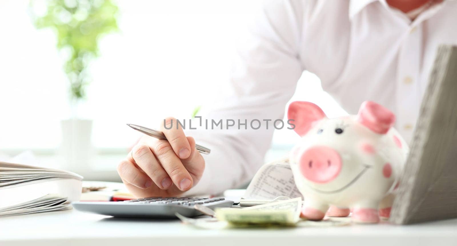 Hand of businessman counting something on calculator device holding financial bills in hand closeup