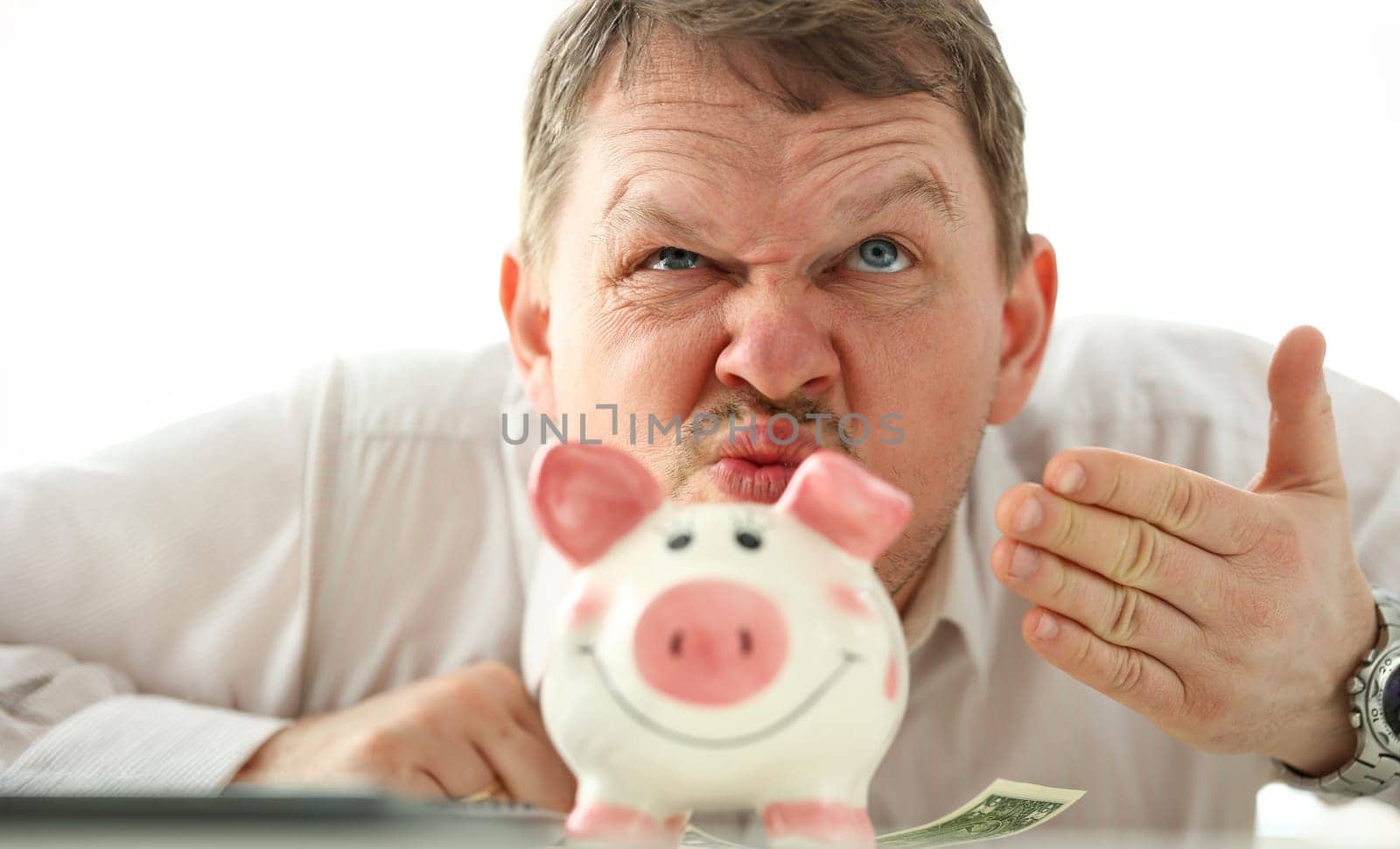 Funny businessman smelling scent of money from piggybank by kuprevich