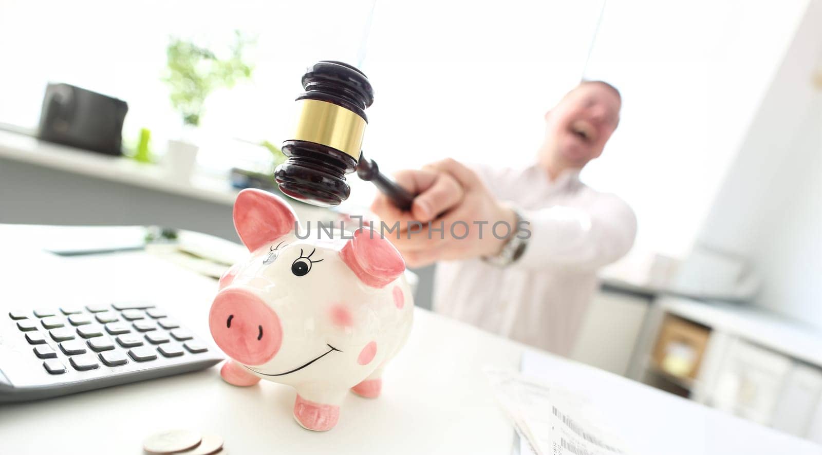 Crazy man with mallet trying to break funny piggybank closeup
