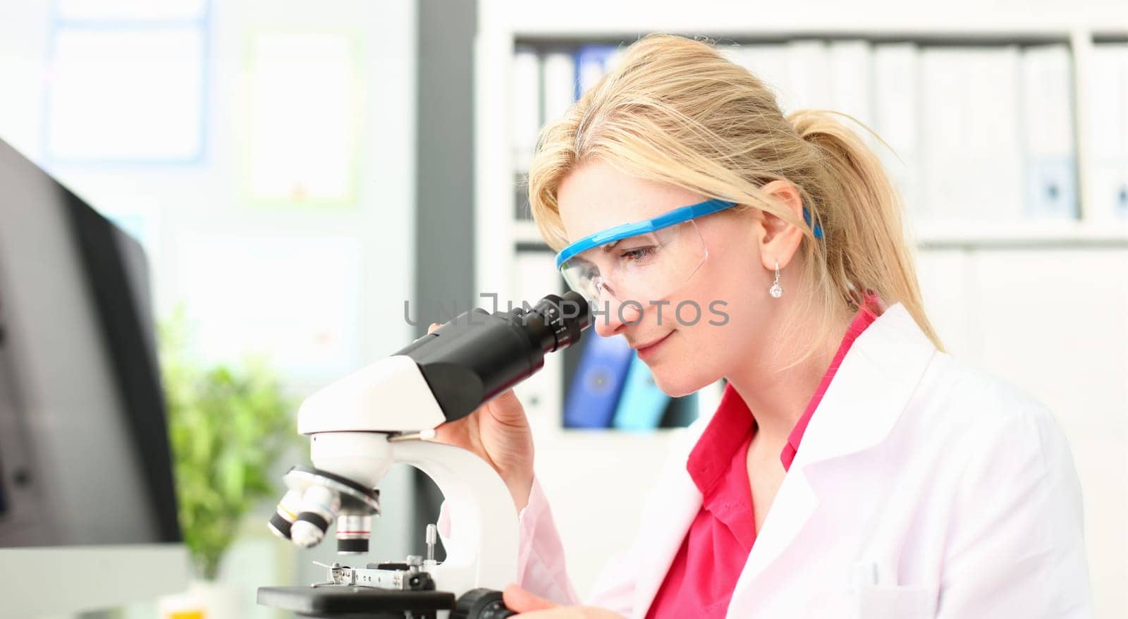 Laboratory Doctor Analyzing Microscope Research. Woman Scientist in Protective Glasses Working on Pharmaceutical Experiment in Lab. Medical Scientific Technology. Chemist Working on Analysis