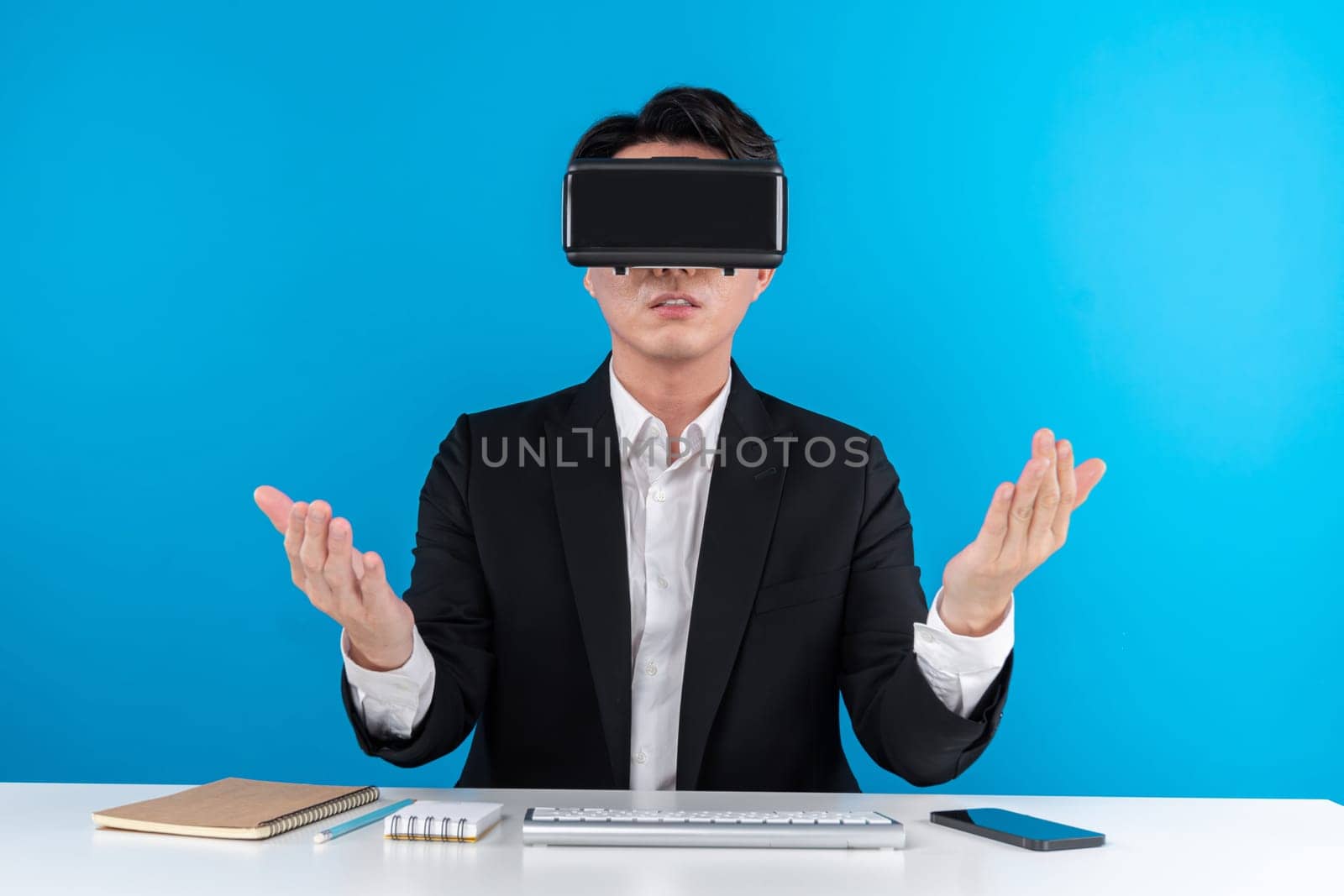 Asian businessman looking thorough VR connecting metaverse meeting in business world news futuristic metaverse, analyzing innovation technology in virtual reality isolated blue copyspace. Contrivance.