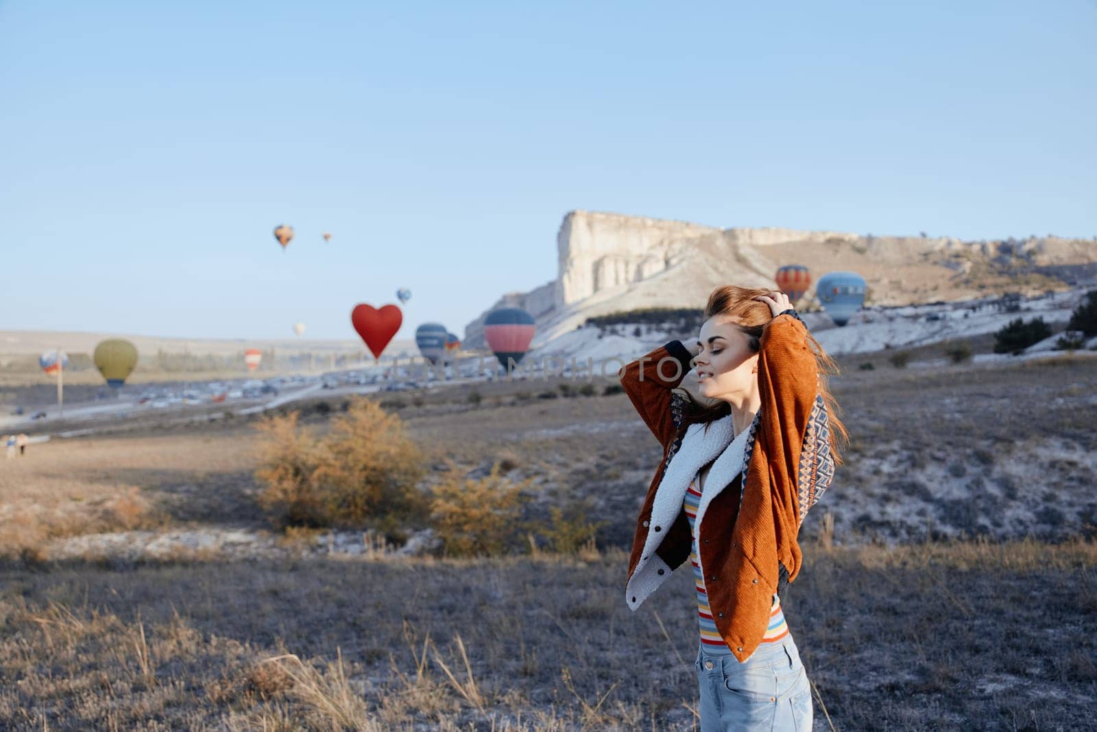 Woman enjoying hot air balloons flying over picturesque field on a sunny day