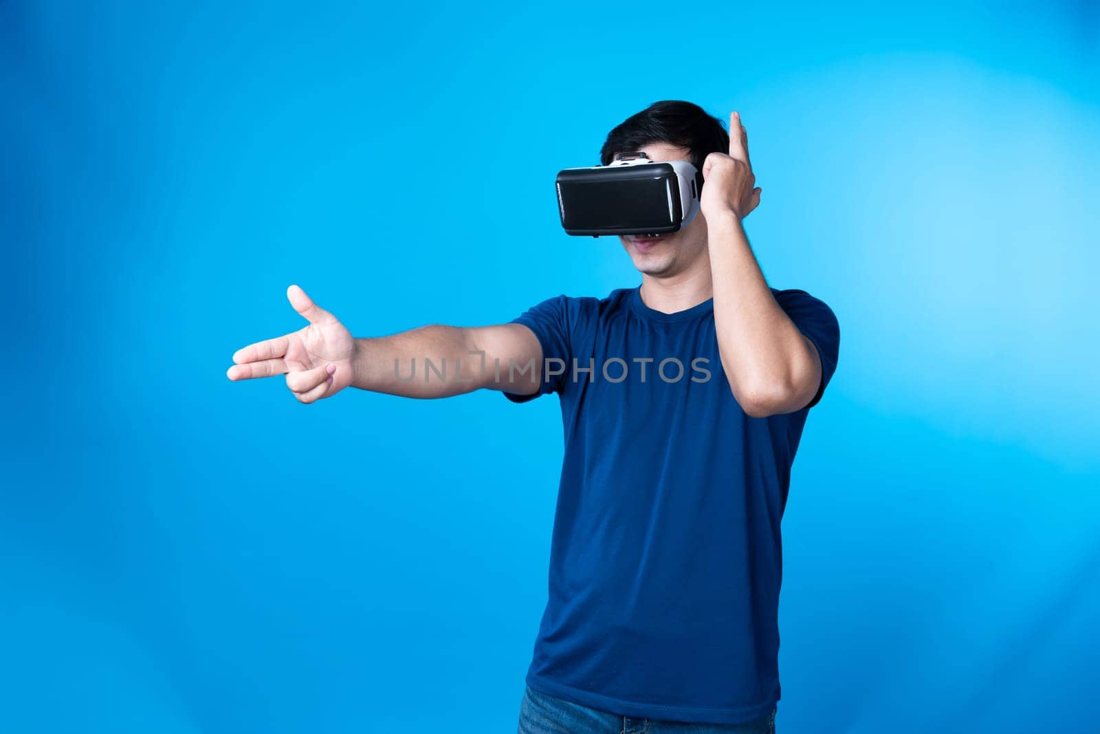 Smart gamer wearing VR turning to metaverse world playing gun shooting hunter isolated blue background connecting to victory animal hunting futuristic technology hologram virtual reality. Contrivance.