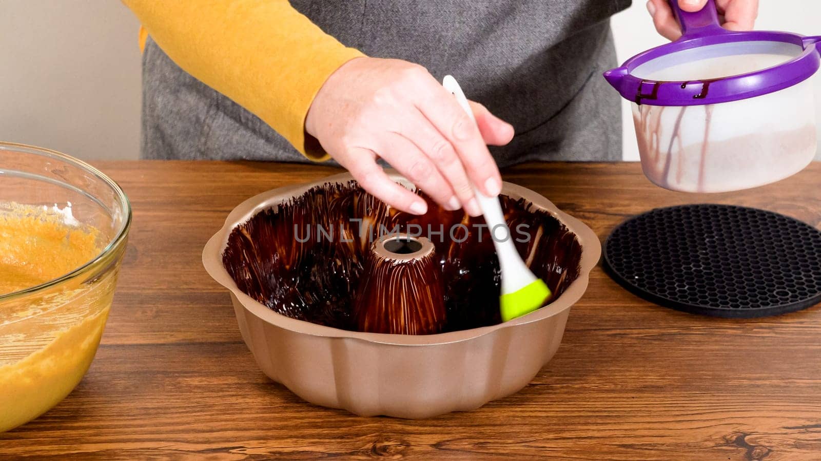 Carefully greasing a bundt cake pan in preparation for baking a delicious gingerbread bundt cake with caramel frosting.