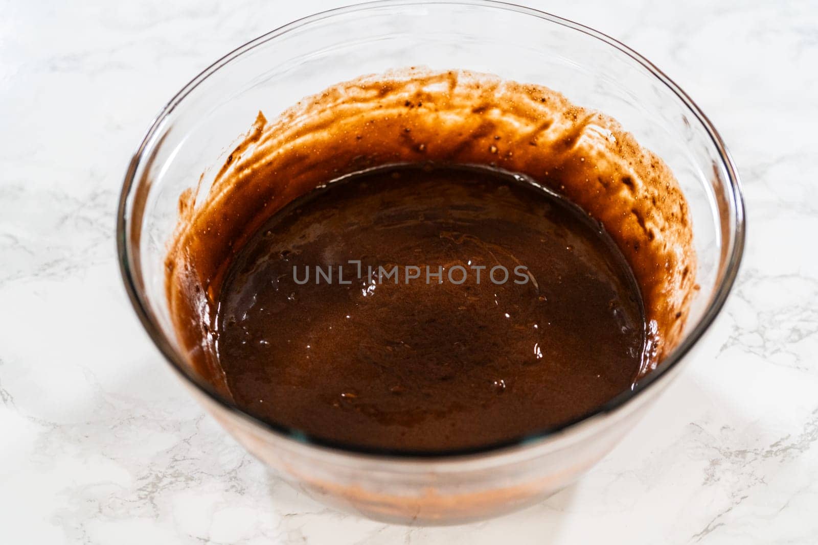 In the process of creating mouthwatering chocolate cupcakes, the first step involves meticulously mixing the ingredients in a glass mixing bowl to make the perfect batter.