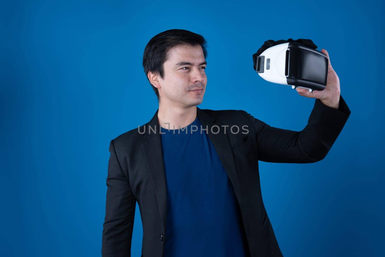 Profile smiling businessman holding VR headset looking metaverse posing portrait isolated blue background futuristic technology in virtual reality in meta finance business digital data. Contrivance.