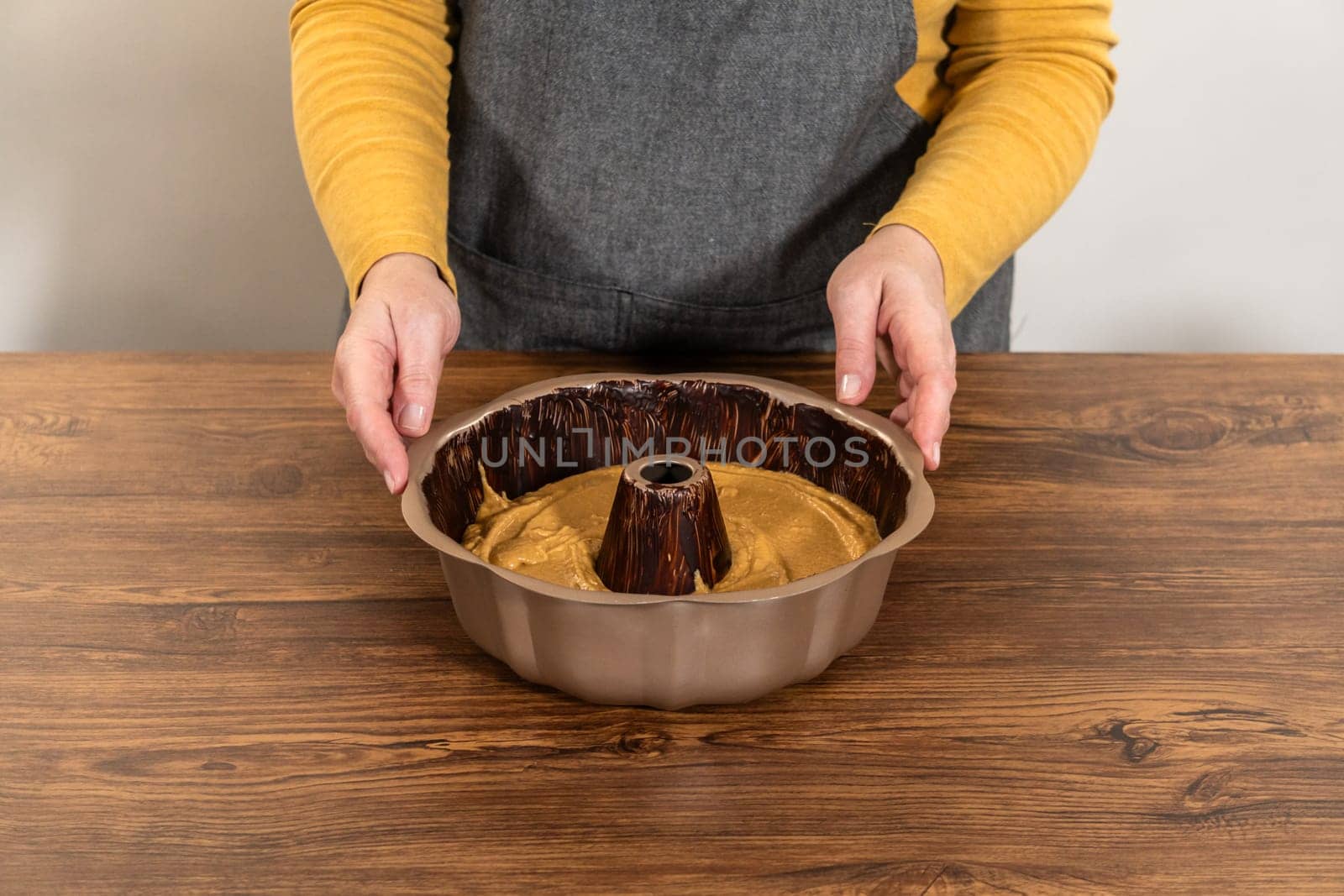 Pouring the gingerbread cake batter into the greased bundt cake pan, ready for a delightful caramel frosting.