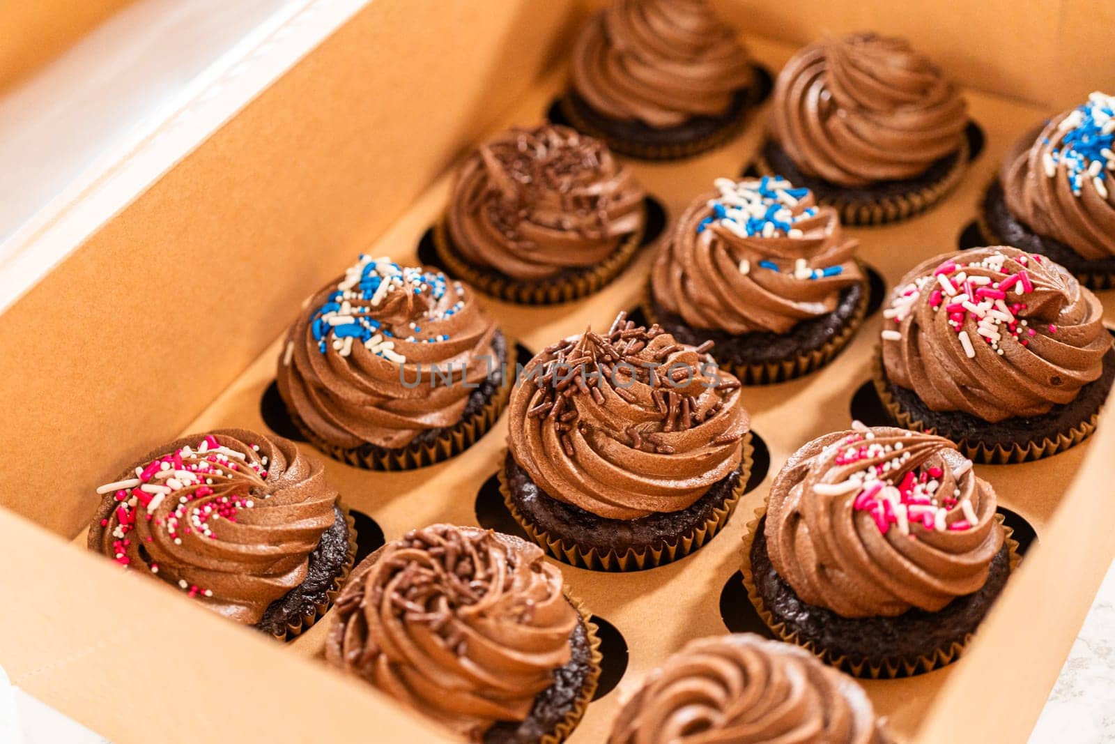 Preparing to share the delicious chocolate cupcakes, the final step involves carefully packaging them into a brown paper cupcake box.