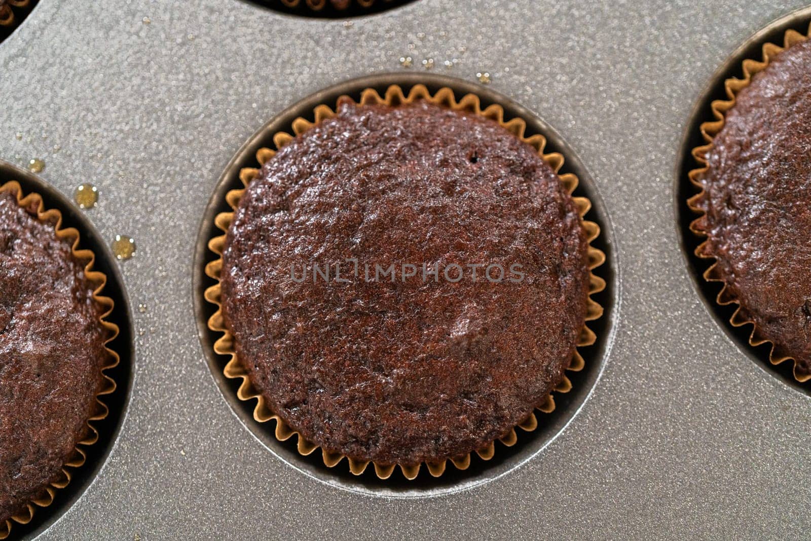 Just out of the oven, these delectable chocolate cupcakes are now resting and cooling on the kitchen counter, filling the air with their tempting aroma.