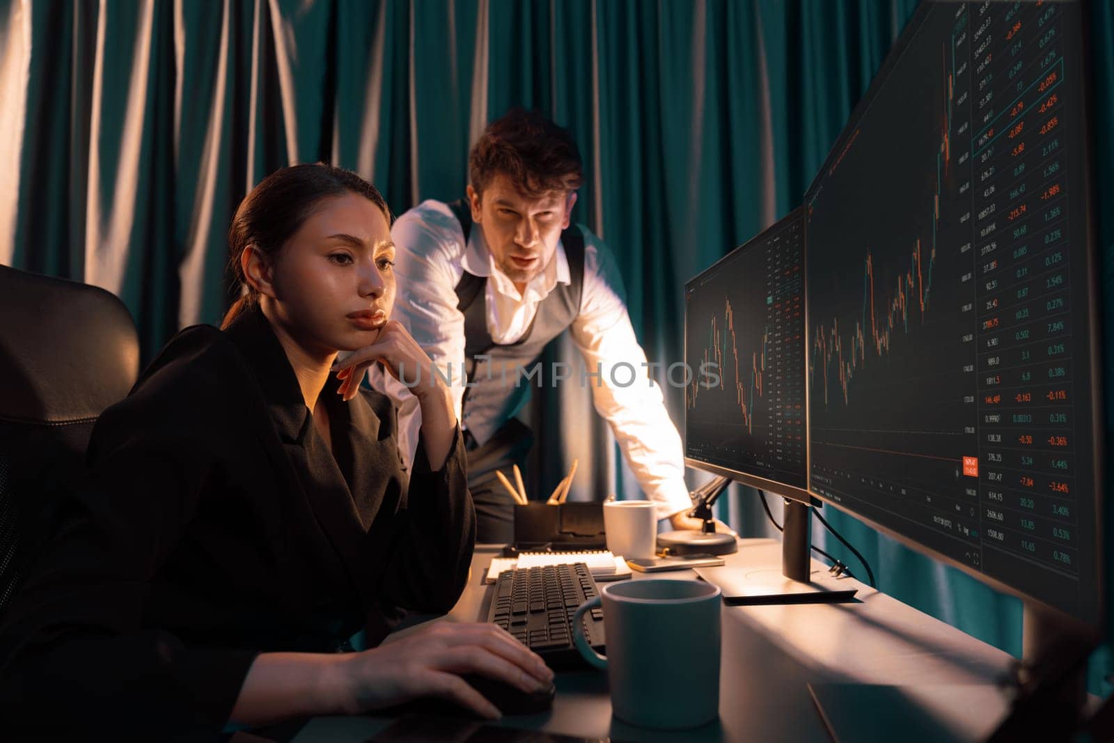 Two business traders discussing on dynamic stock exchange currency rate risk investment, pointing profit or loss value forecast on pc screens side view at night neon lighting office room. Postulate.