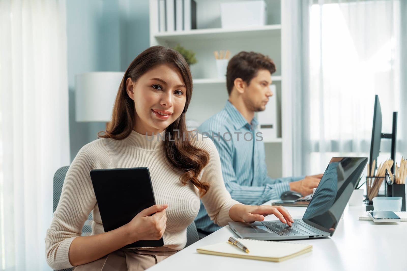 Smiling beautiful woman working on laptop aligning taking note to pose for looking at camera photo shooting portrait profile's business with smart coworker at modern office at morning time. Postulate.