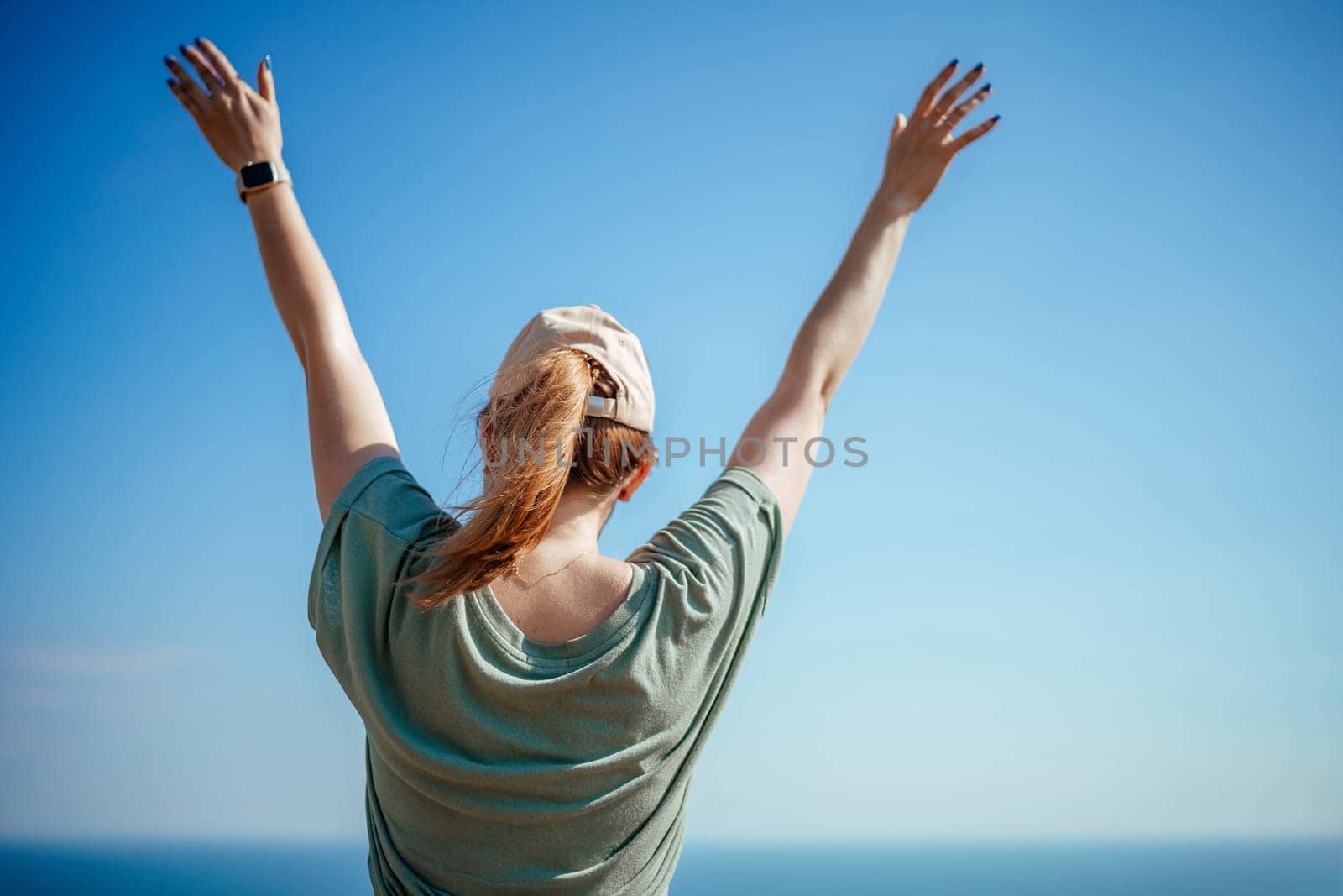 Woman tourist sky sea. Happy traveler woman in hat enjoys vacation raised her hands up.