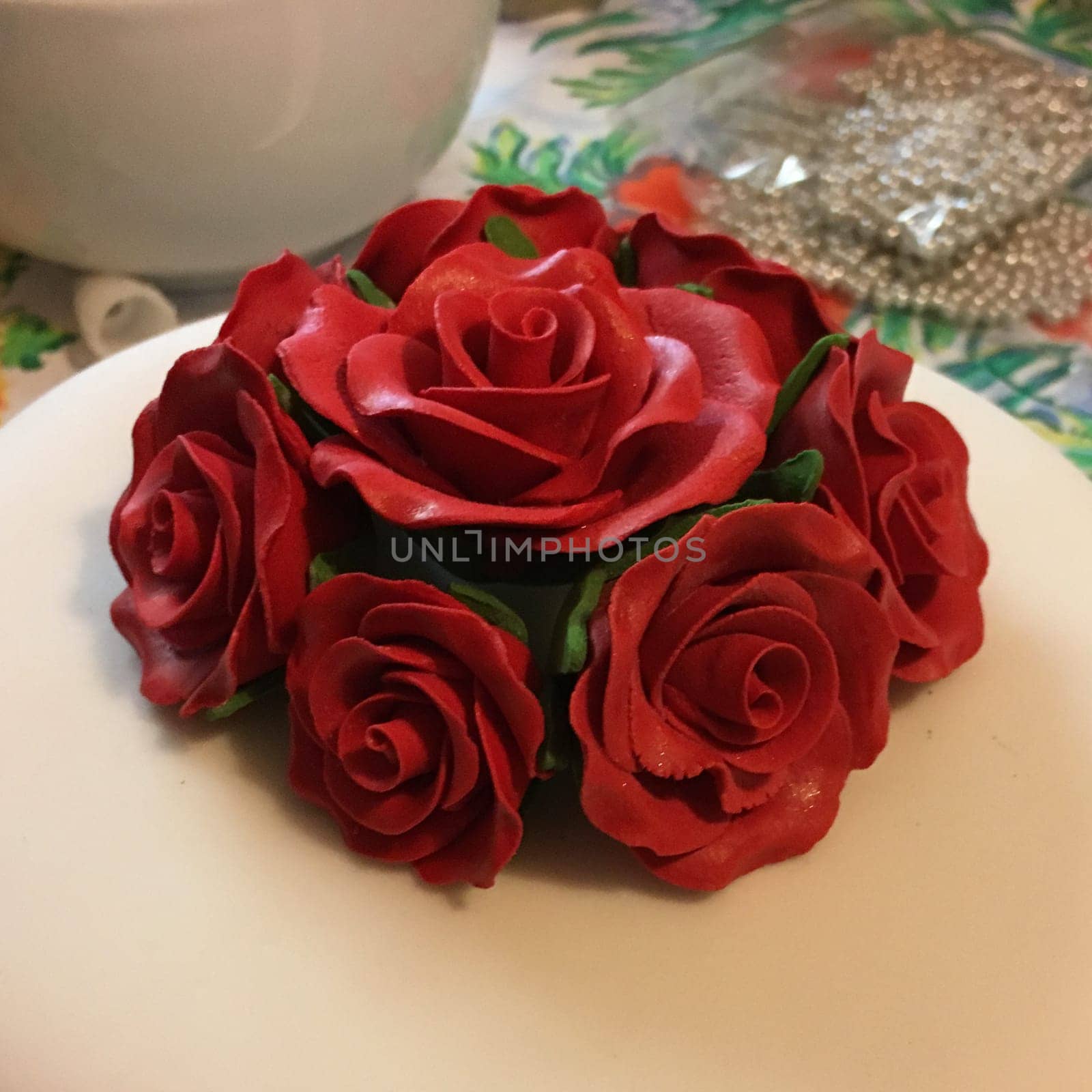 A close-up of a decorative arrangement of red roses made from fondant, placed on a white surface.