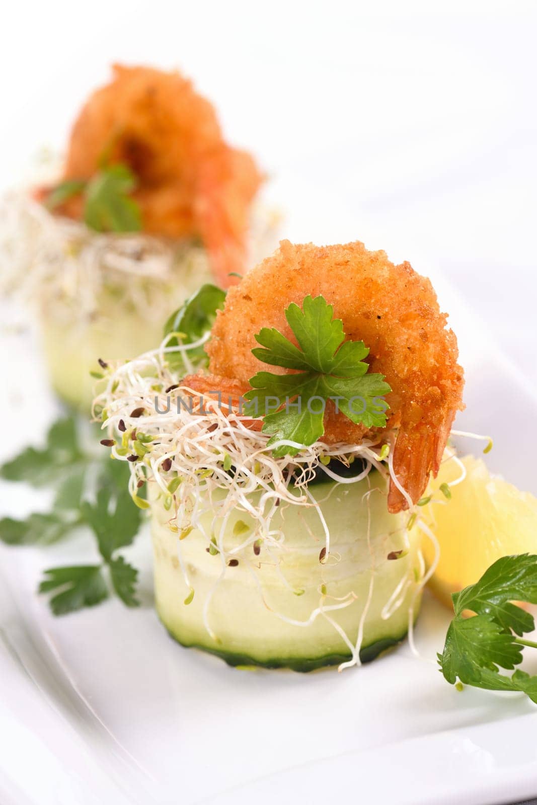 Cucumber appetizer with fried breaded shrimp on a bed of microgreens