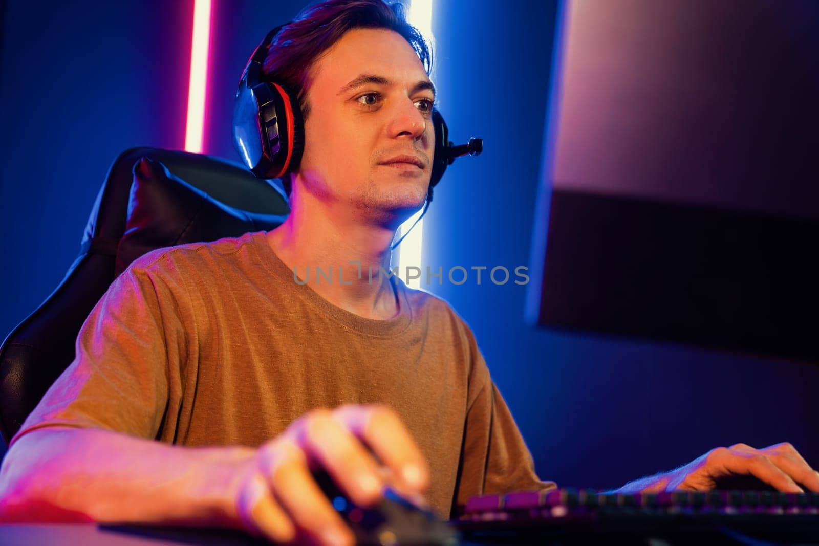 Host channel of gaming smart streamer playing online game to be winner, wearing headphone with viewers live steaming on media social online for selected team competition at neon light room. Pecuniary.