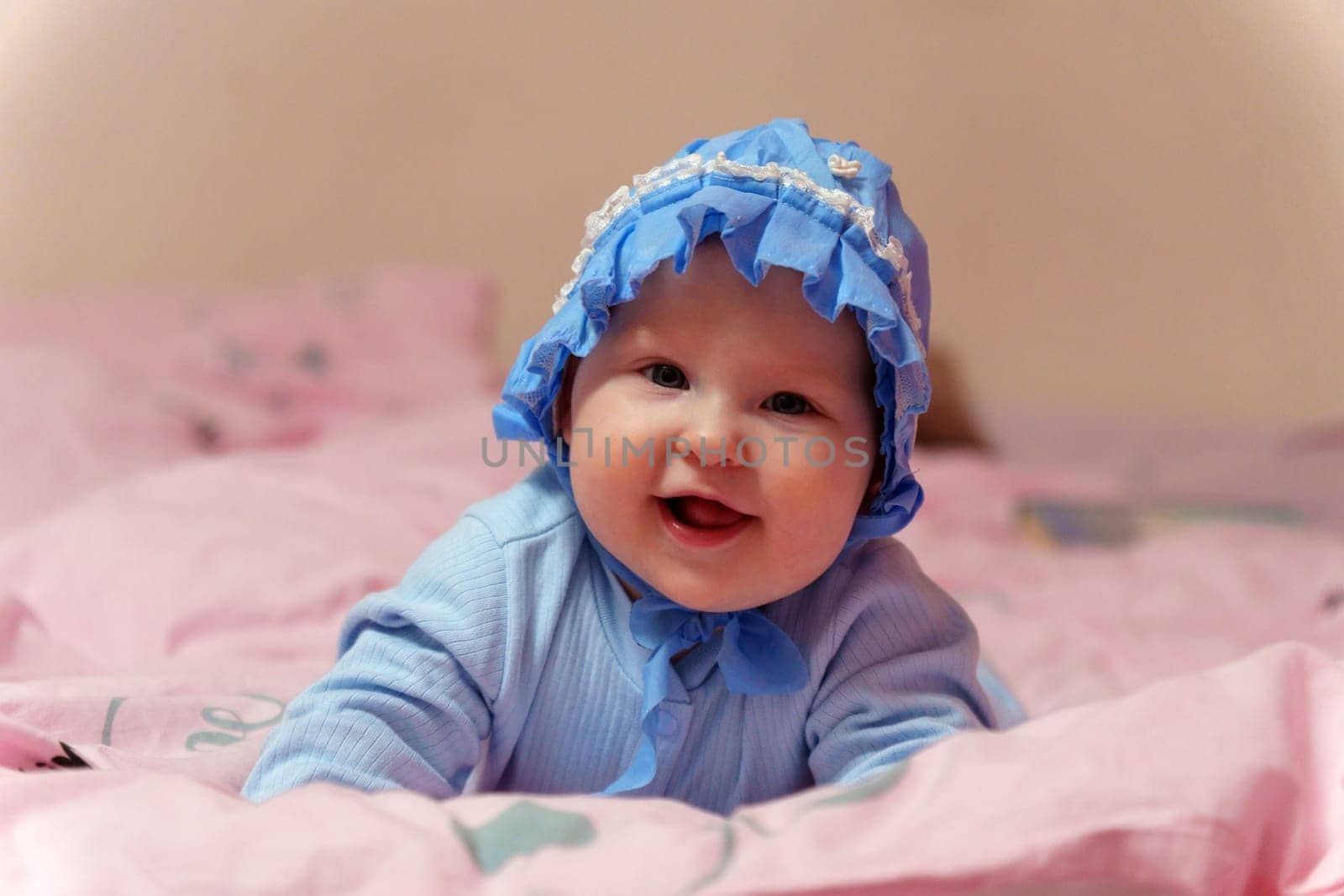 Sweet baby with a blue bonnet peacefully on a soft pink blanket.