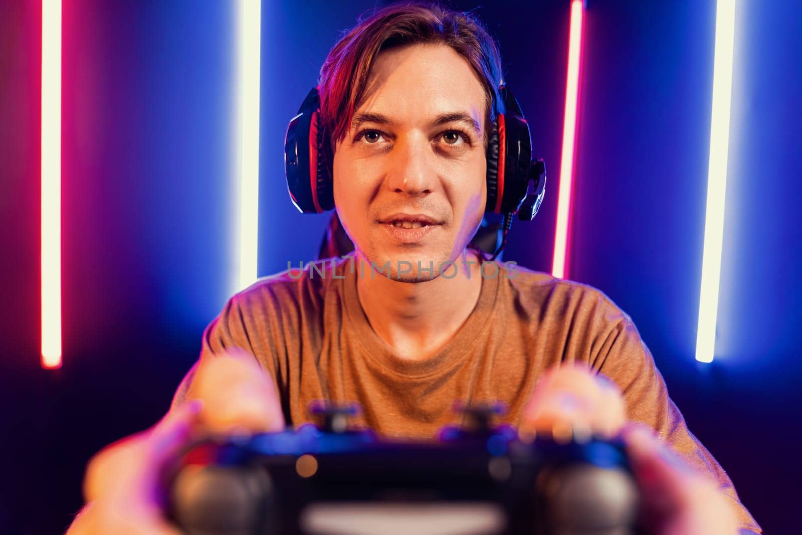 Enjoy smart gaming streamer with control joystick, playing game online of live streaming social media group with team skilled players on computer at modern technology cyber neon light room. Pecuniary.