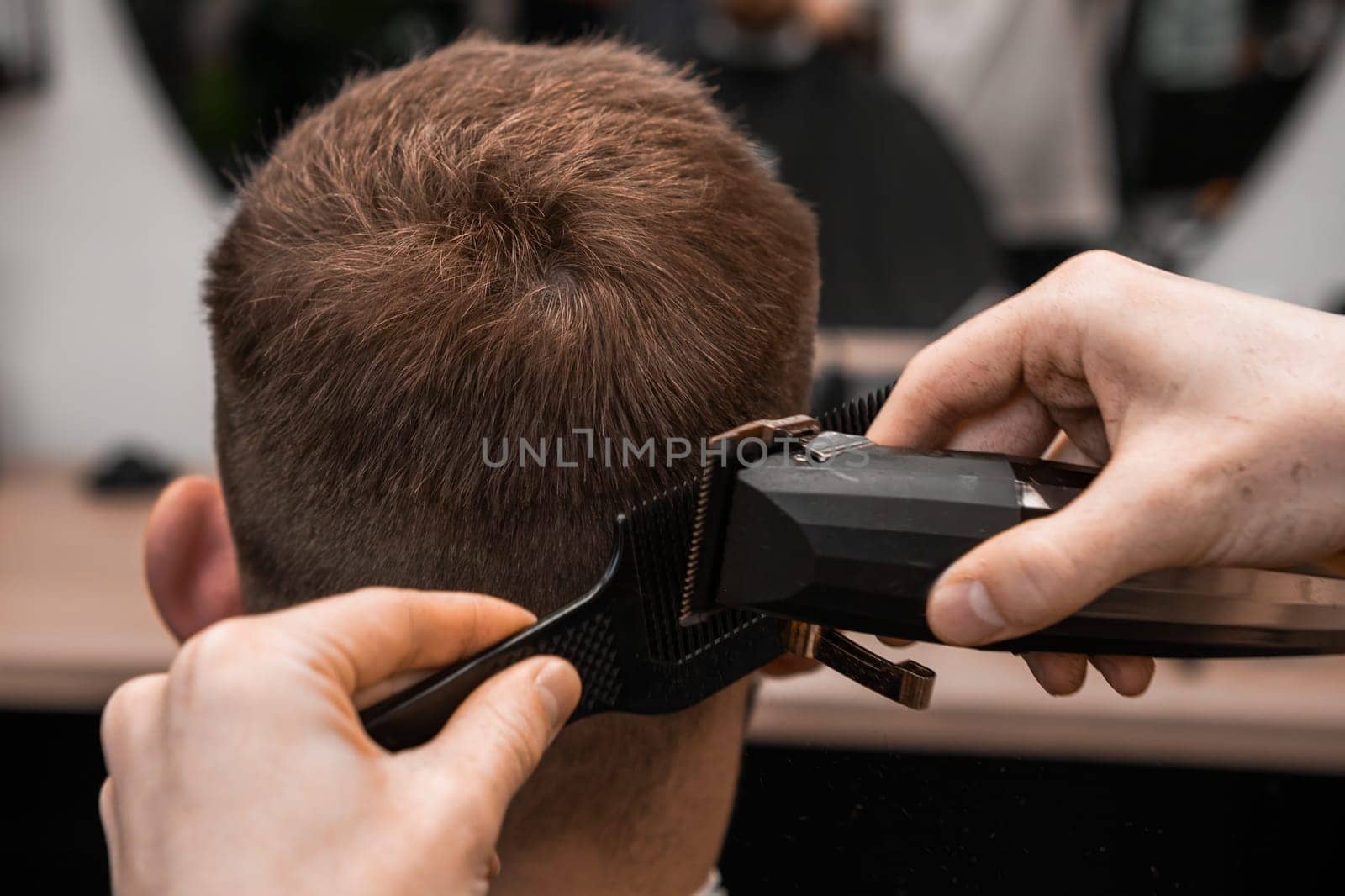 Hairdresser shaves the mans hair on the occiput in the contemporary barbershop