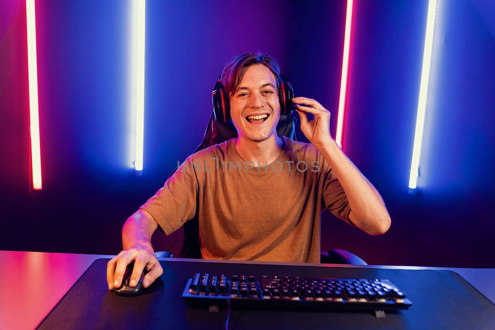 Host channel of gaming smart streamer playing online game to be winner, wearing headphone with viewers live steaming on media social online for selected team competition at neon light room. Pecuniary.