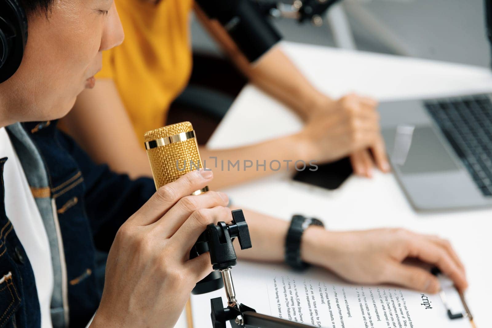 Selective focusing on hands with writing script note of radio influencer host with microphone on channel social media online live streaming on blurry background at morning at studio record. Infobahn.