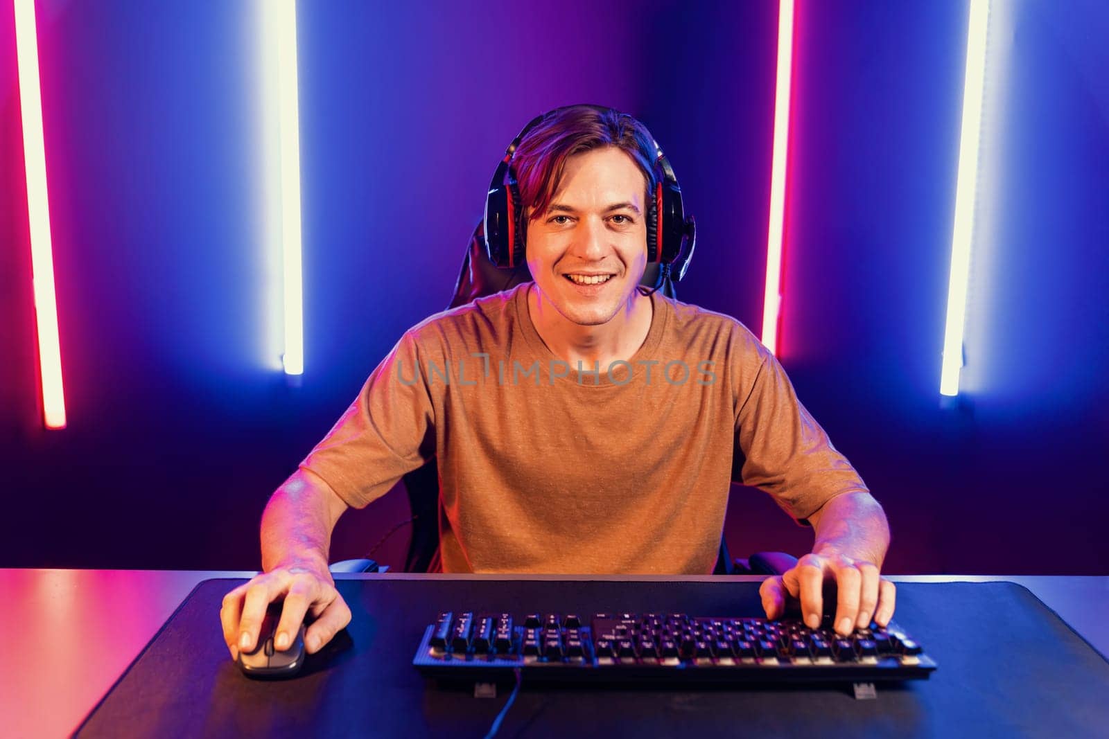 Host channel of gaming smart streamer playing online game to be winner, wearing headphone with viewers live steaming on media social online for selected team competition at neon light room. Pecuniary.