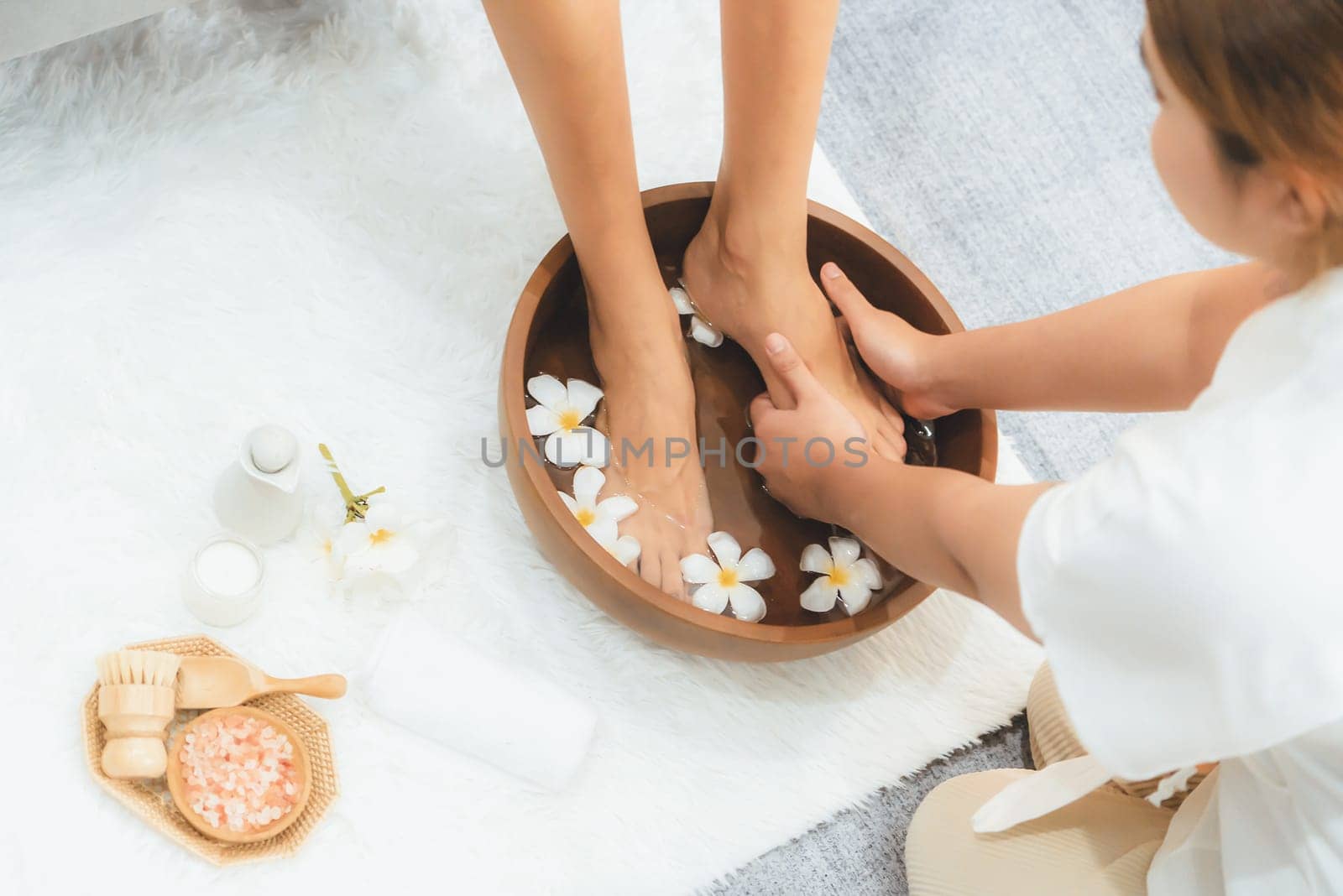 Woman indulges in blissful foot massage at luxurious spa salon while masseur give reflexology therapy in gentle day light ambiance resort or hotel foot spa. Quiescent