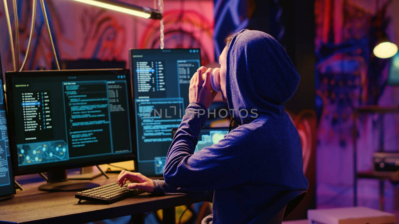 Hacker drinking coffee at underground bunker desk while using network vulnerabilities to exploit servers, trying to break computer systems at night. Lone wolf cybercriminal breaching networks