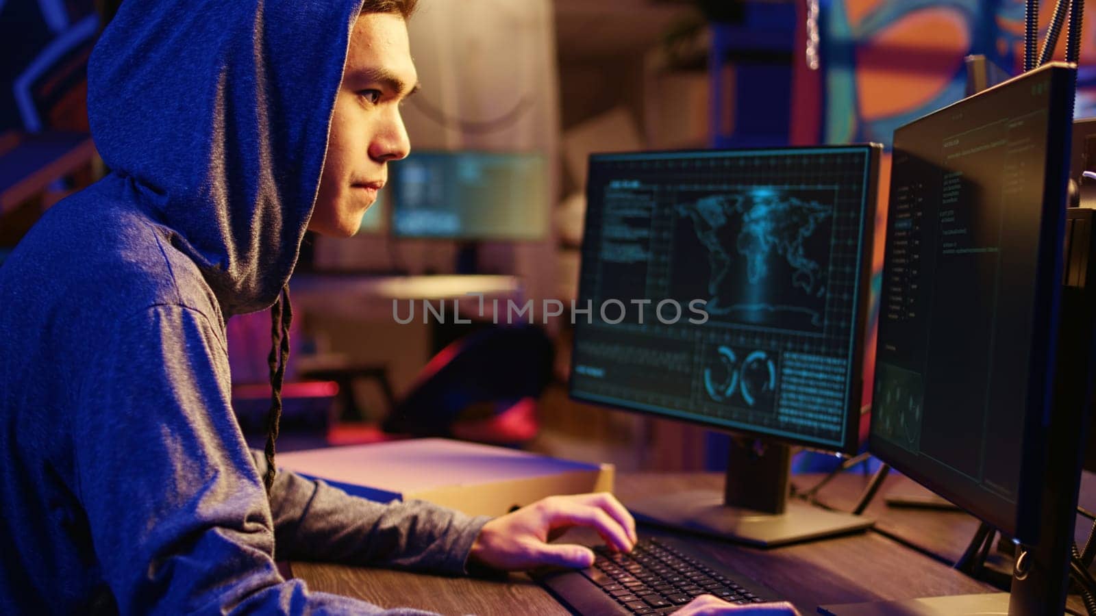 Asian hacker doing international espionage warfare for his government to steal state secrets from another countries, anxiously looking over shoulder, afraid of being caught and going to jail
