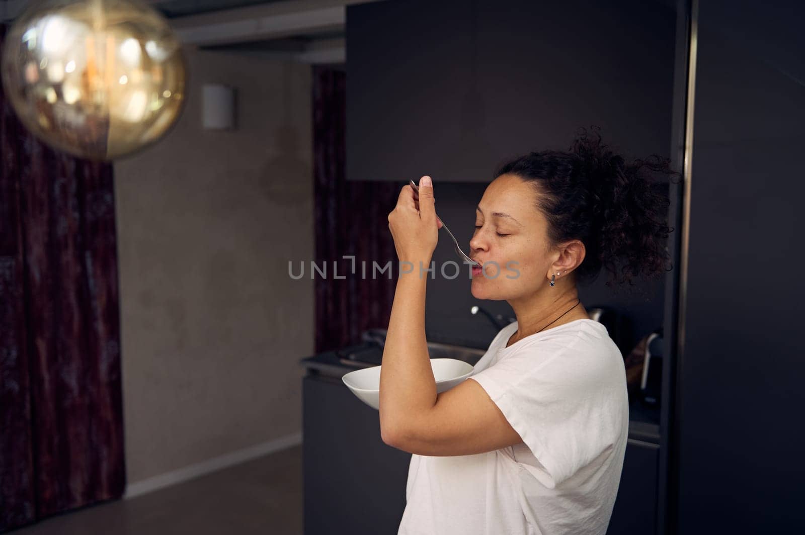 Side portrait of a happy woman eating breakfast in the morning