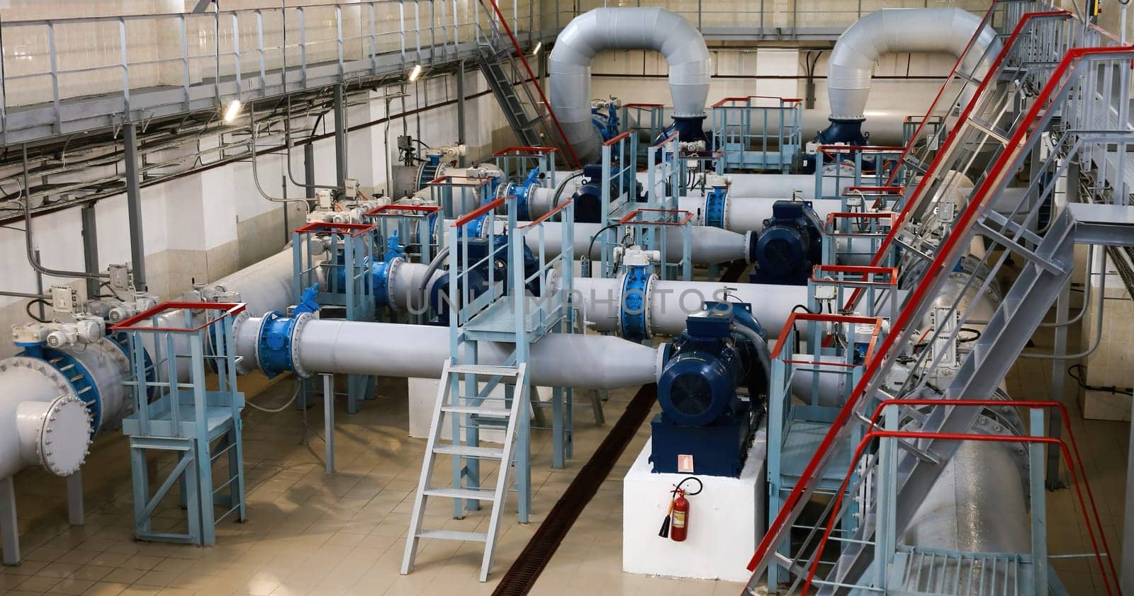 The industrial water pumping station features well-maintained pumps, pipes, and valves, brightly lit and showcasing precise engineering in efficient water management.