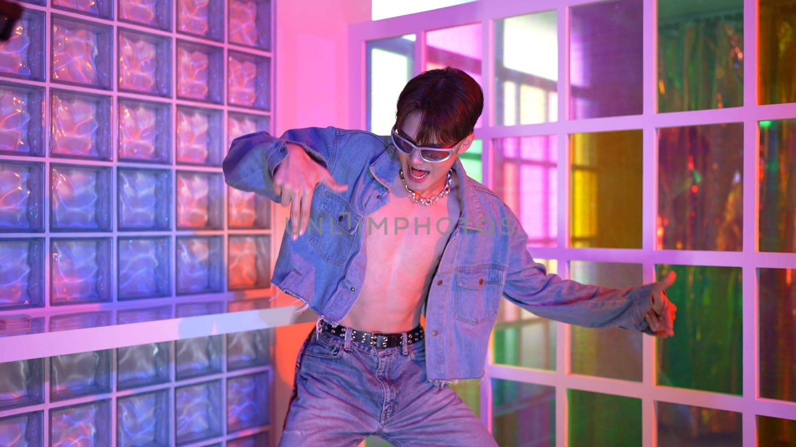 Professional happy hipster moving arm while dancing at center surrounded by diverse friend cheering him. Attractive asian break performing energetic footstep with neon light at nightclub. Regalement.