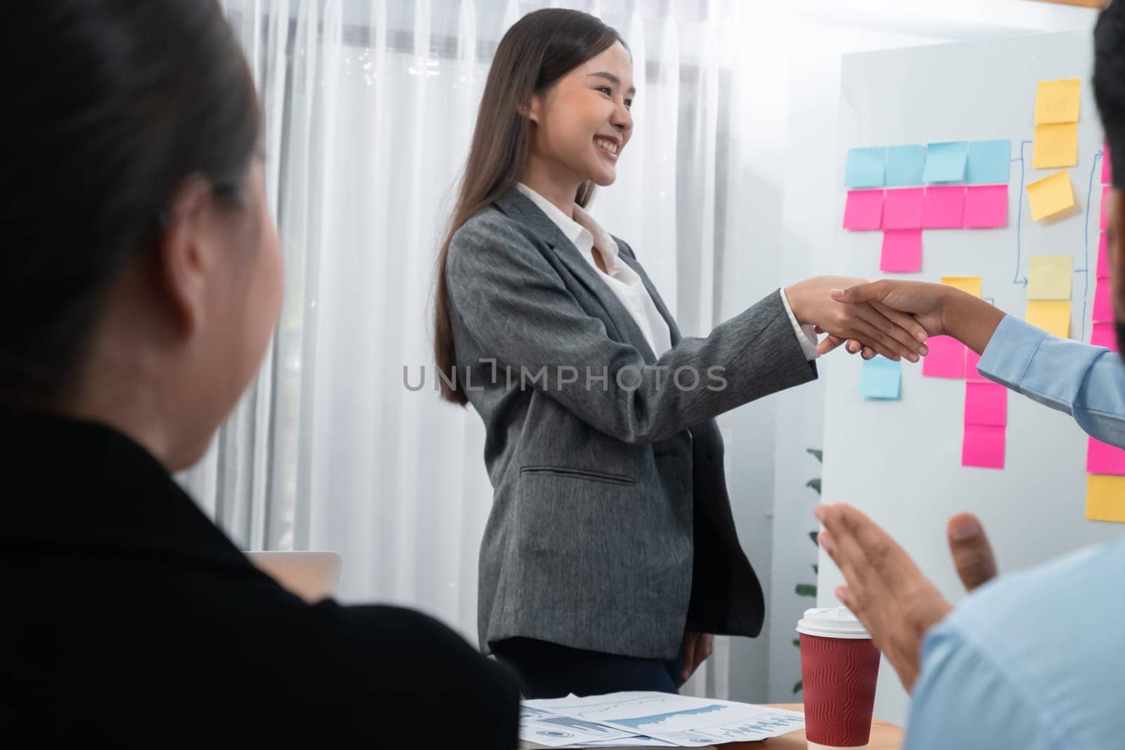 Diverse coworker celebrate with handshake and teamwork in corporate workplace. Happy business people united by handshaking after successful meeting or business presentation on data analysis. Concord