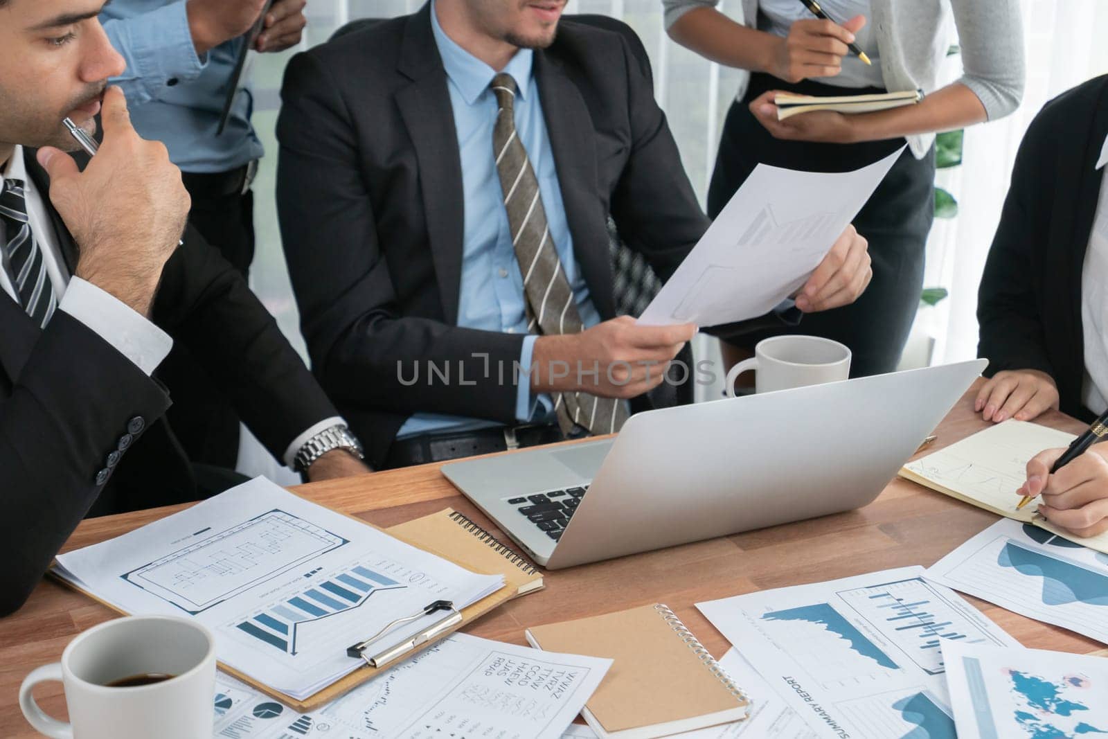 Diverse group of business analyst team analyzing financial data report paper on office table. Chart and graph dashboard by business intelligence analysis for strategic marketing planning Habiliment