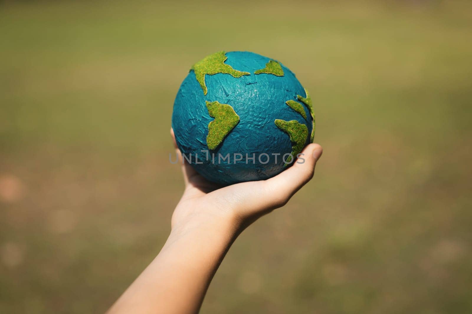 Young boy's hand holding planet Earth globe at natural park background as Earth day to save this planet with ESG principle and environment friendly energy for brighter future. Gyre