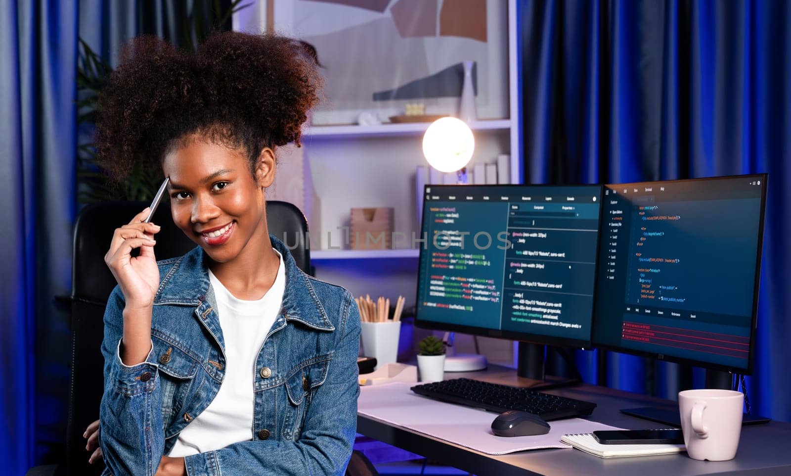 Young African wearing jeans shirt, IT developer presenting program on computer screens displaying coded data of application and website, creating innovative updated software version. Tastemaker.