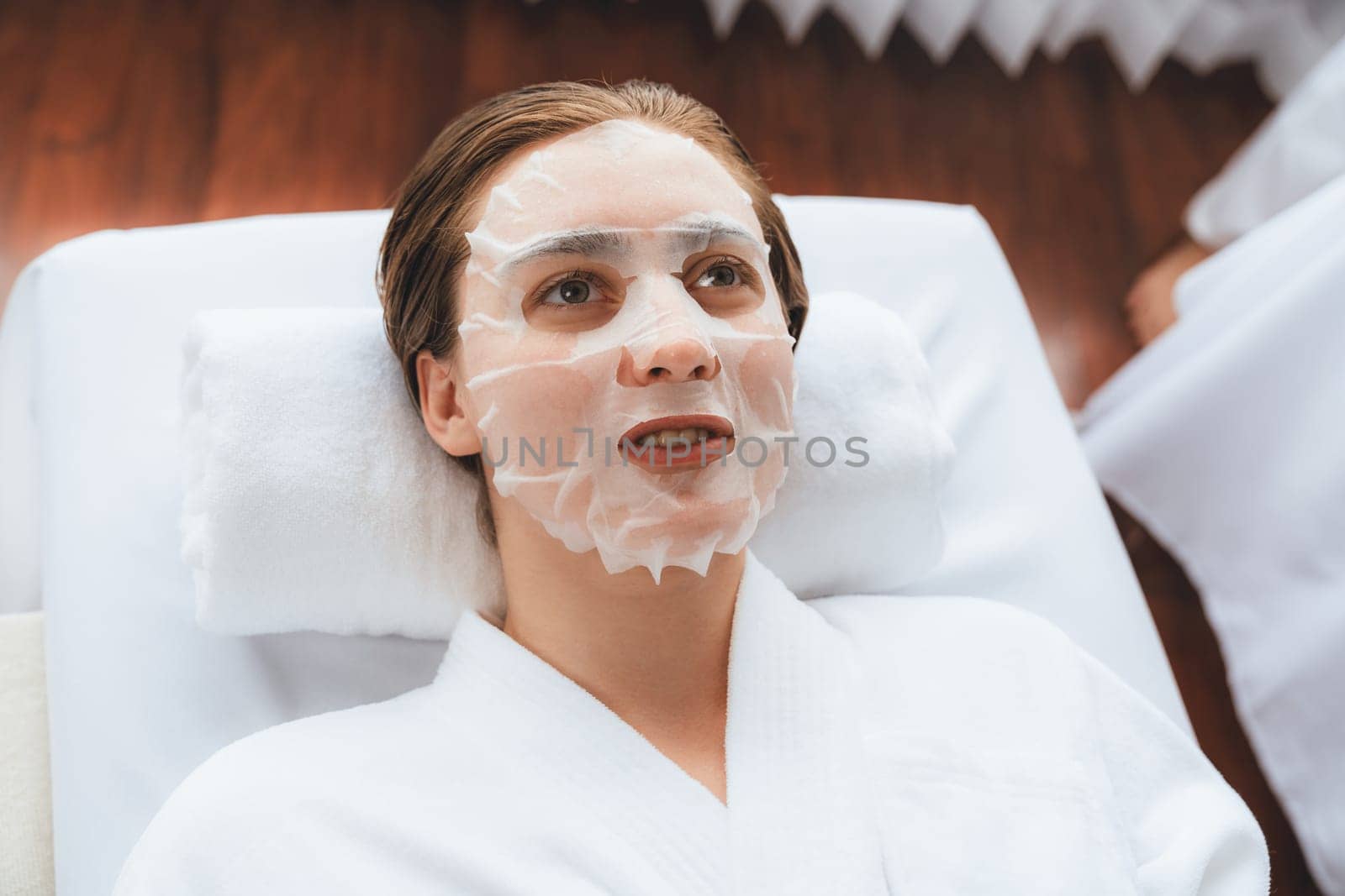 Serene modern daylight ambiance of spa salon, woman customer indulges in rejuvenating with facial skincare mask. Facial skin treatment and beauty cosmetology procedure for face. Quiescent