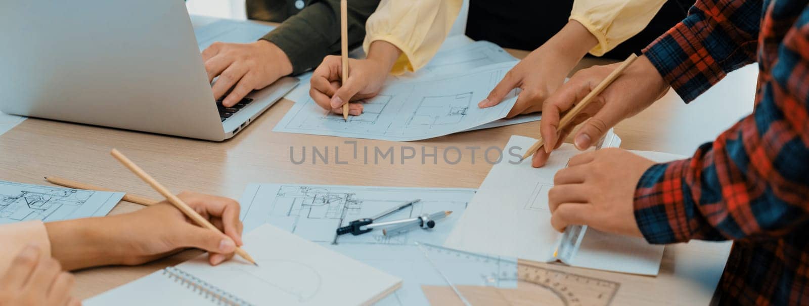 Skilled architect team using architectural equipment during colleague discussion about building design at meeting table with blueprint scatter around. Closeup. Focus on hand. Delineation.