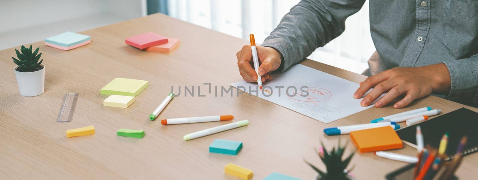 Skilled businessman brainstorms marketing ideas using mind maps. Successful male startup leader drafts financial plan on table with sticky notes scatter around. Closeup. Focus on hand.Variegated.