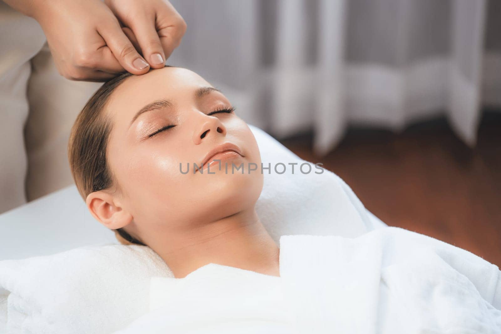 Caucasian woman enjoying relaxing anti-stress head massage and pampering facial beauty skin recreation leisure in dayspa modern light ambient at luxury resort or hotel spa salon. Quiescent