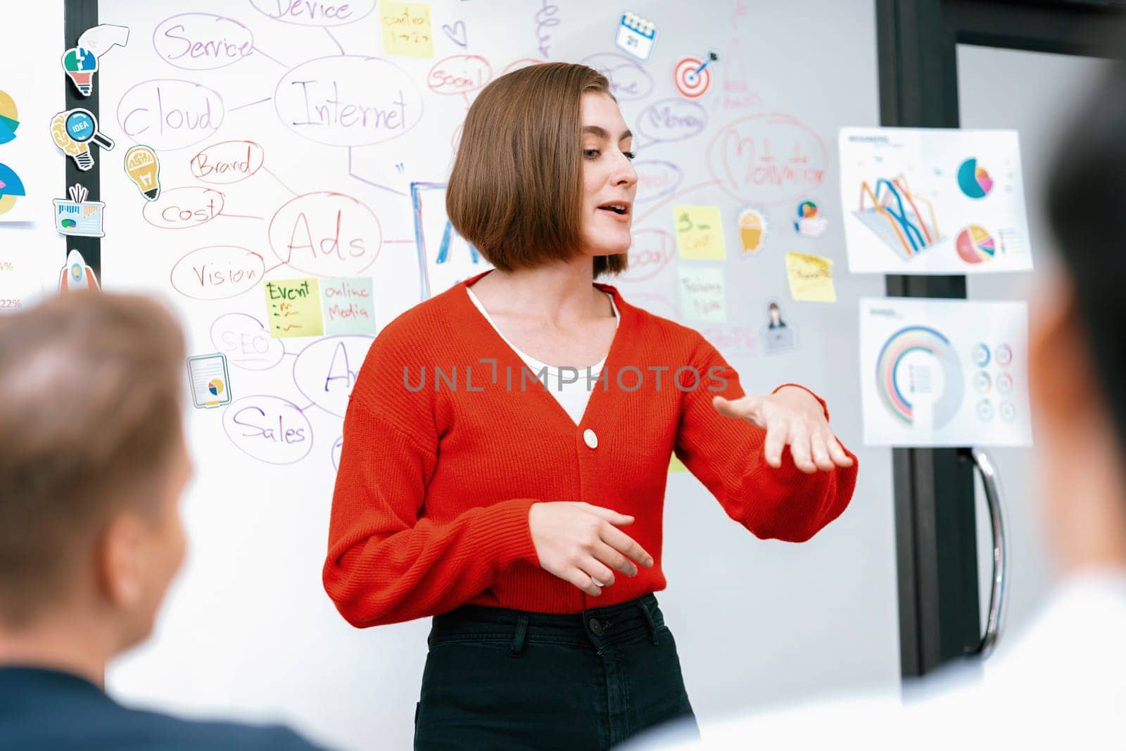 Professional attractive female leader presents creative marketing plan by using brainstorming mind mapping statistic graph and colorful sticky note at modern business meeting room. Immaculate.