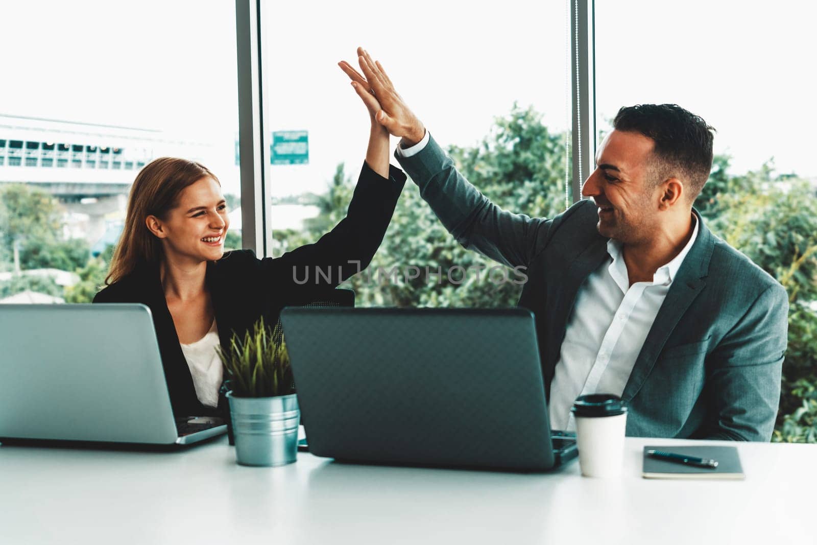 Success business partner - Businesswoman and businessman celebrating together in modern workplace office. People corporate teamwork concept. uds