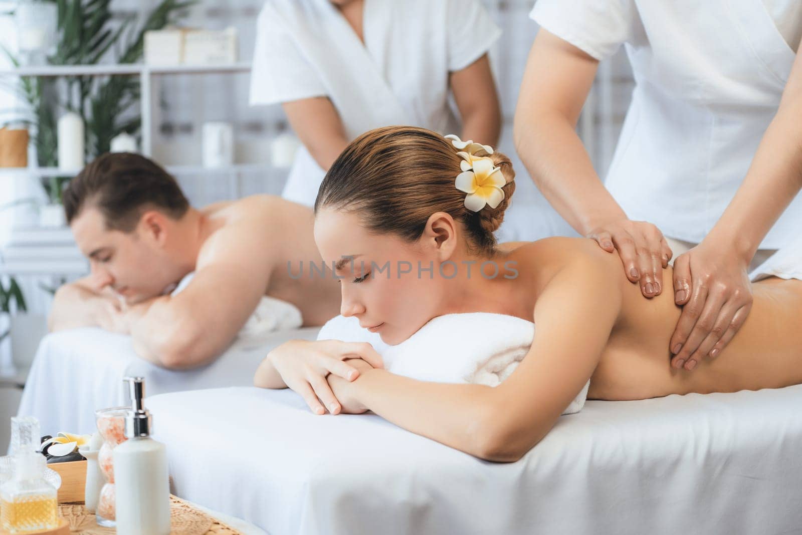 Caucasian couple customer enjoying relaxing anti-stress spa massage and pampering with beauty skin recreation leisure in day light ambient salon spa at luxury resort or hotel. Quiescent