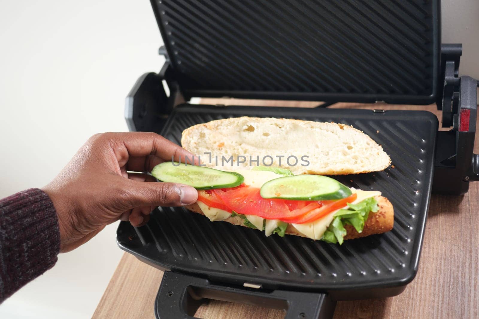 A person is retrieving a grilled sandwich from the grill.