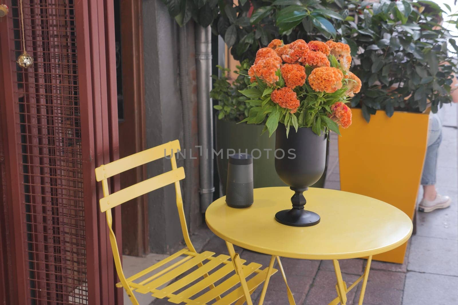 A yellow table with a vase filled with bright orange flowers adorning it, adding a touch of vibrant color to the room